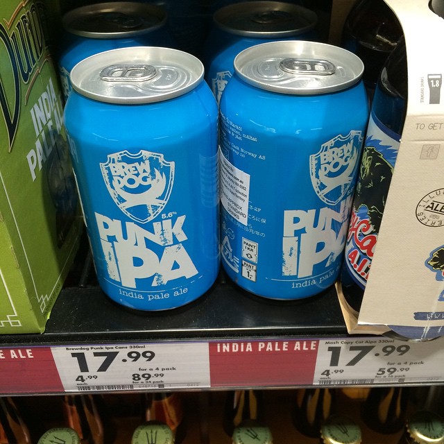 Four blue BrewDog Punk IPA cans on a store shelf with price tags below.