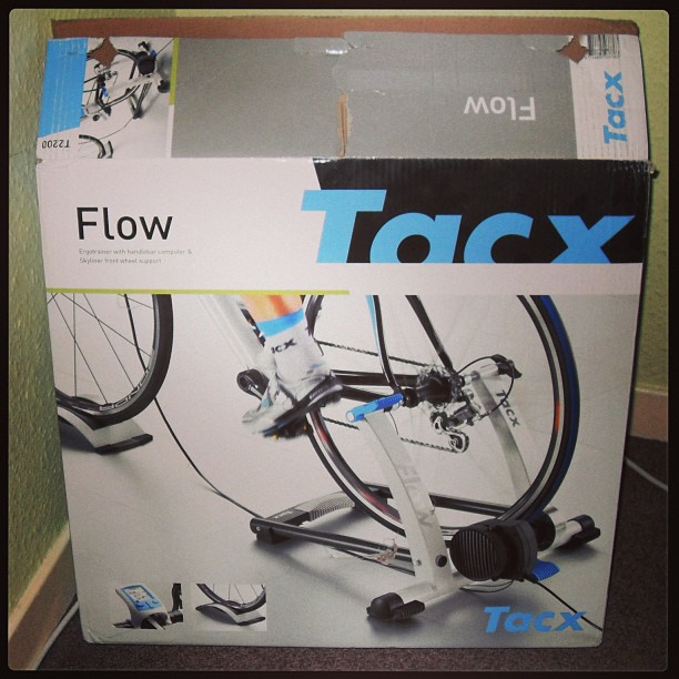 Tacx Flow bike trainer box with a photo of a bicycle mounted on the trainer and a person pedaling.