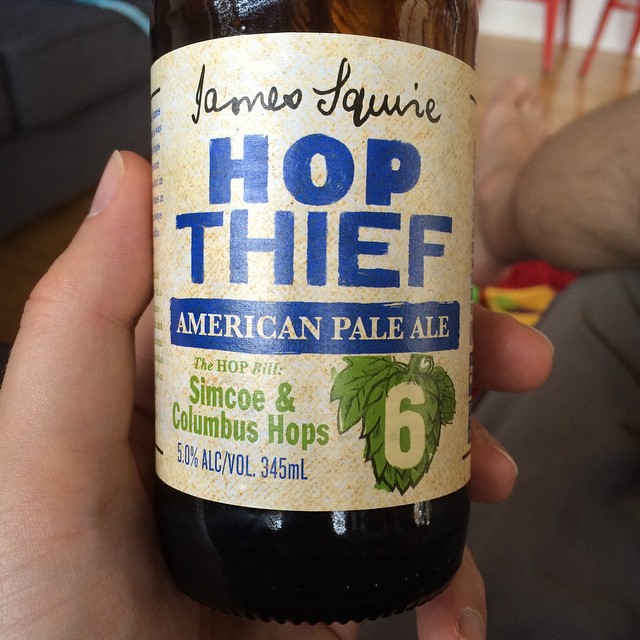 Hand holding a James Squire Hop Thief American Pale Ale bottle labeled Simcoe and Columbus hops, 5.0% alc/vol, 345 mL.