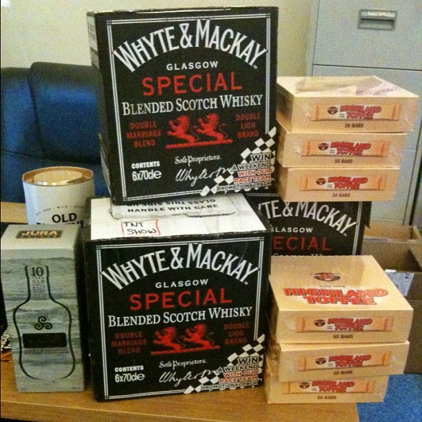 Boxes of Whyte & Mackay Scotch whisky stacked beside several packs of Cubebad Toffee and a Jura box on a table.