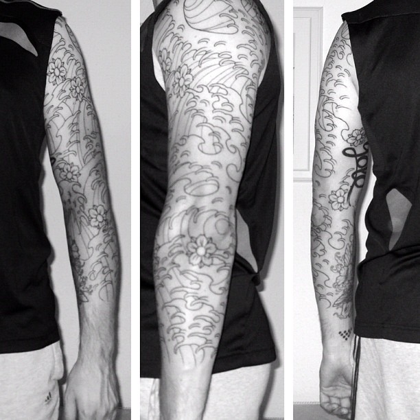 Three views of a person in a black sleeveless shirt showing a full arm tattoo with waves and flowers.