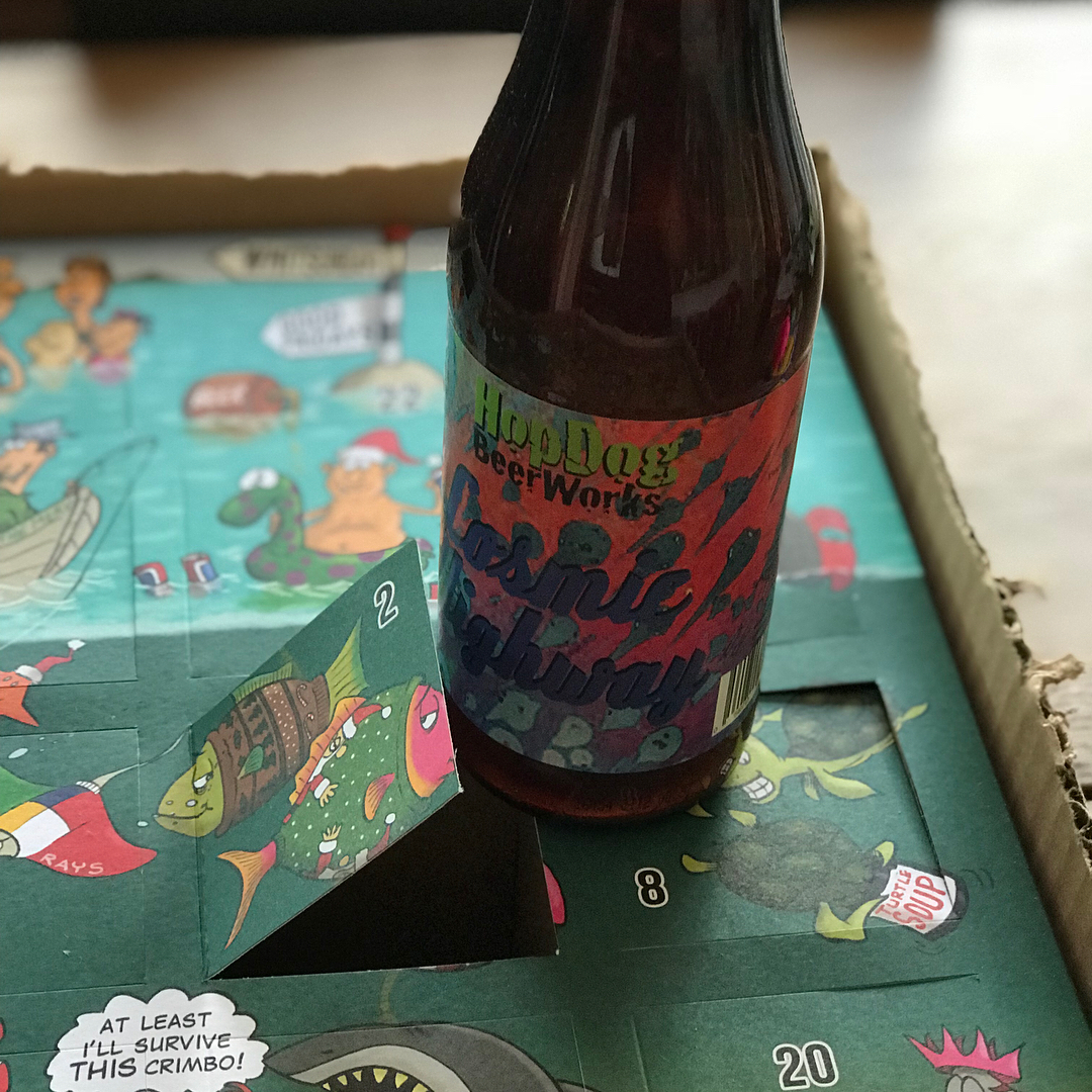 Beer bottle standing on a colorful advent calendar with an opened flap marked 2.