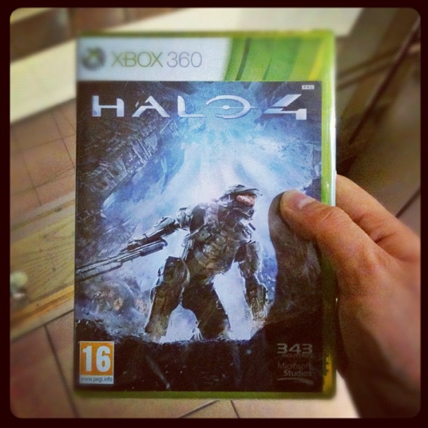 Hand holding an Xbox 360 Halo 4 game case with Master Chief on the cover.