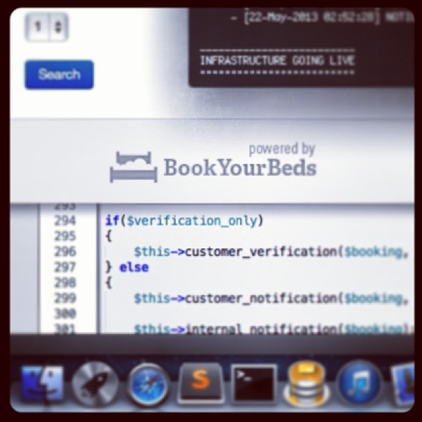Laptop screen showing a booking site logo, code editor, search button, and Mac dock icons.
