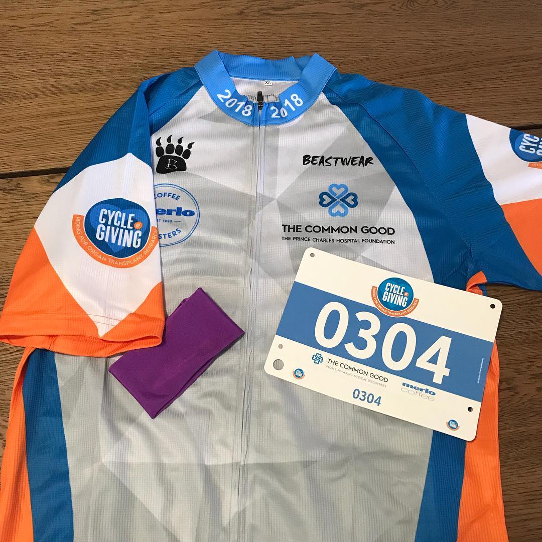 Cycling jersey with blue and orange sleeves, a race bib numbered 0304, and a purple headband laid on a wooden table.