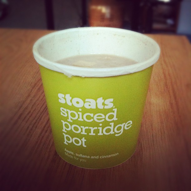 Green Stoats spiced porridge pot filled with porridge on a wooden table.