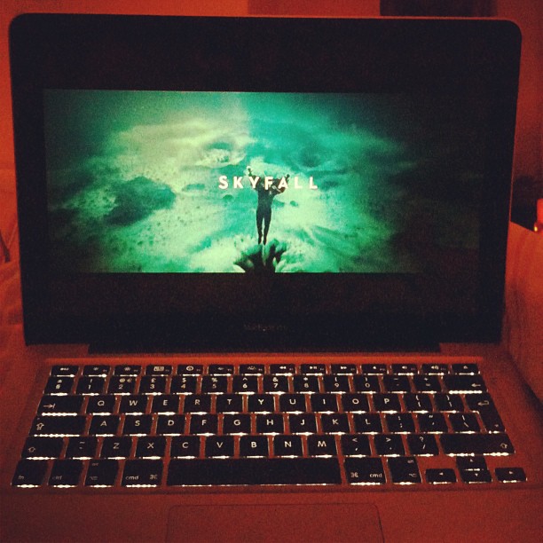 Laptop with backlit keyboard displaying the title "Skyfall" on a green-tinted screen.
