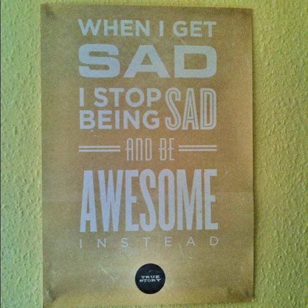 Poster on a textured wall reading, “When I get sad I stop being sad and be awesome instead,” with a small “true story” circle at bottom.