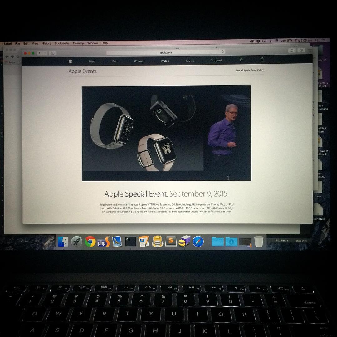 Laptop screen displaying an Apple Events webpage with Apple Watch images and a presenter, above a backlit keyboard.