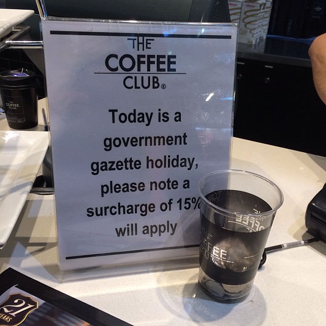 Counter sign at The Coffee Club says a 15% surcharge will apply today due to a government gazette holiday.