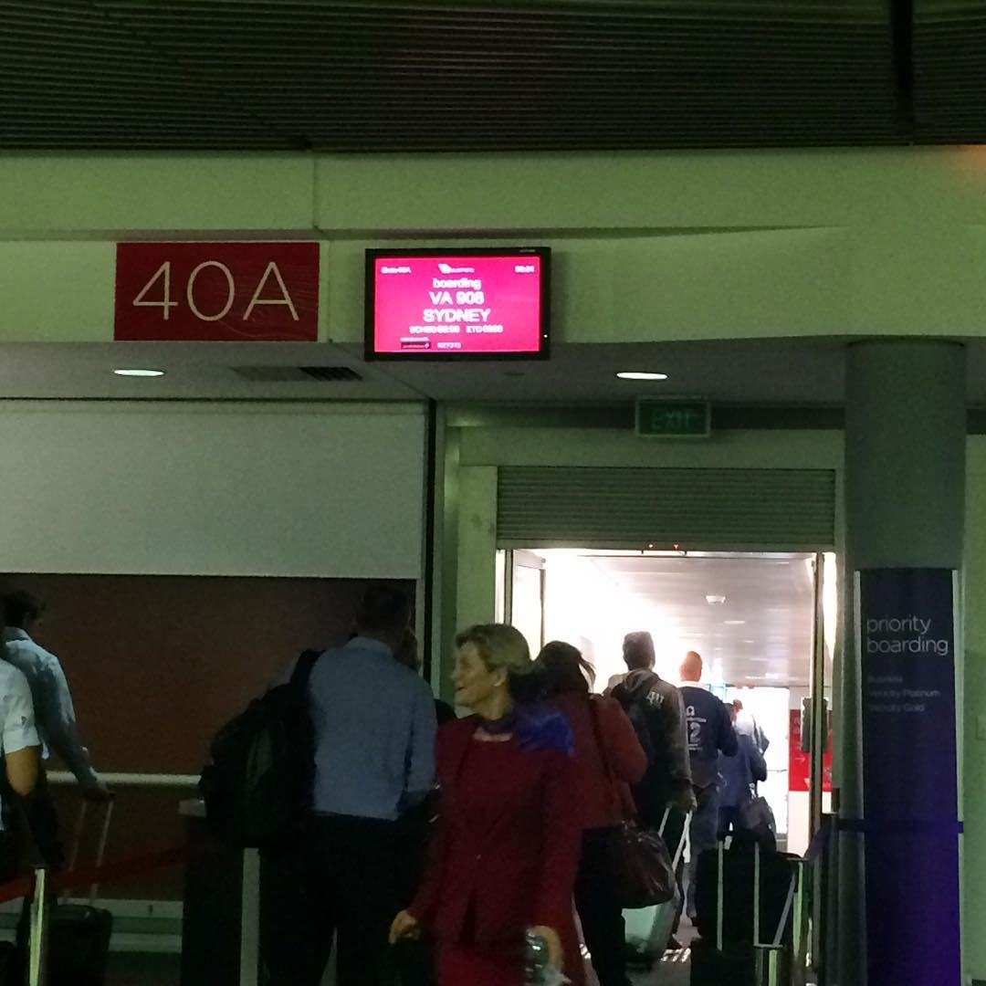 Passengers boarding at gate 40A beneath a screen showing Virgin Australia flight VA 808 to Sydney.