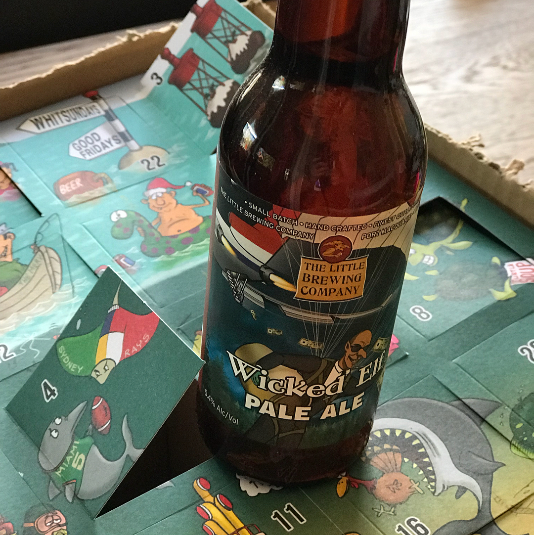 Brown beer bottle on an illustrated advent calendar with opened numbered flaps and cartoon sea-themed drawings.