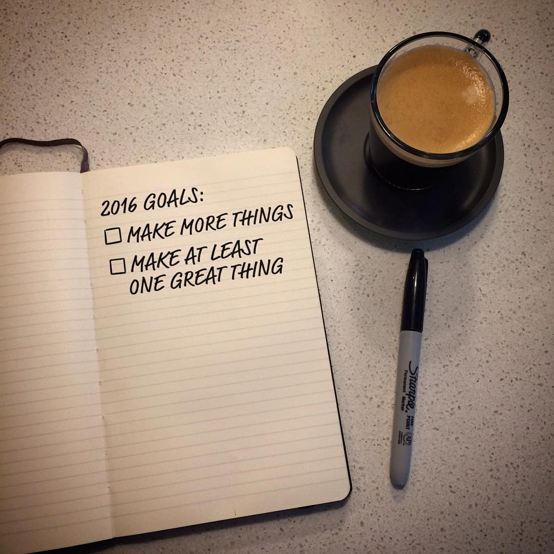 Open notebook with handwritten 2016 goals, a black marker, and a cup of coffee on a speckled countertop.