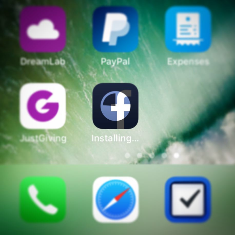 Smartphone home screen showing app icons including DreamLab, PayPal, Expenses, JustGiving, and Facebook installing, with Phone, Safari, and a checklist app belo