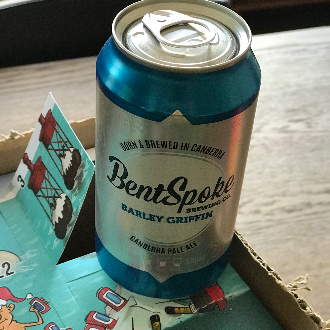 Blue BentSpoke Barley Griffin pale ale can standing in a cardboard box on a wooden table.