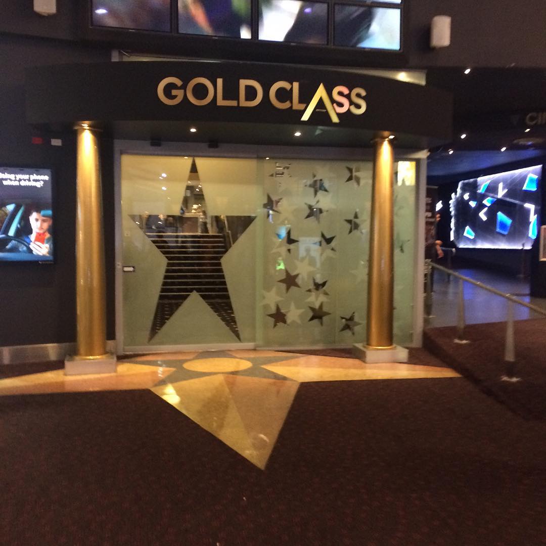 Entrance to GOLD CLASS cinema with glass doors decorated with star shapes and two gold columns.
