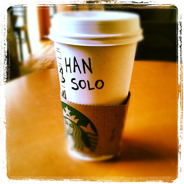 Starbucks takeaway cup on a table with "HAN SOLO" written in black marker on the side.