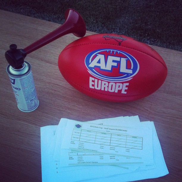 Red AFL Europe football on a wooden table beside an air horn can and a stack of scorecards.