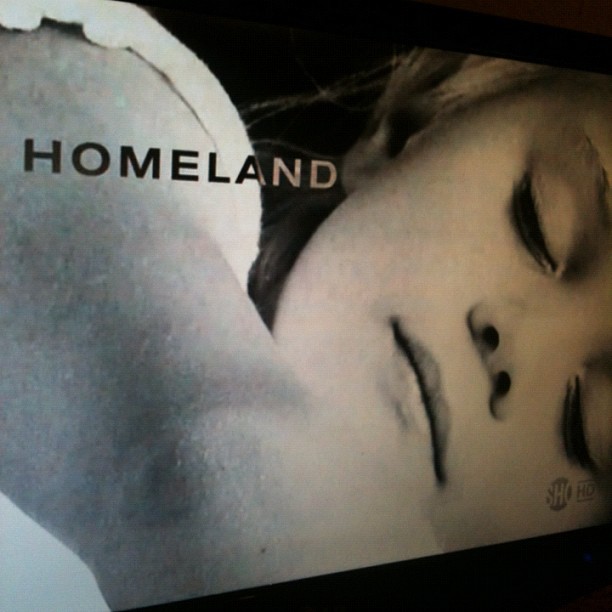 Close-up of a woman's face lying sideways with the word "HOMELAND" across the image.