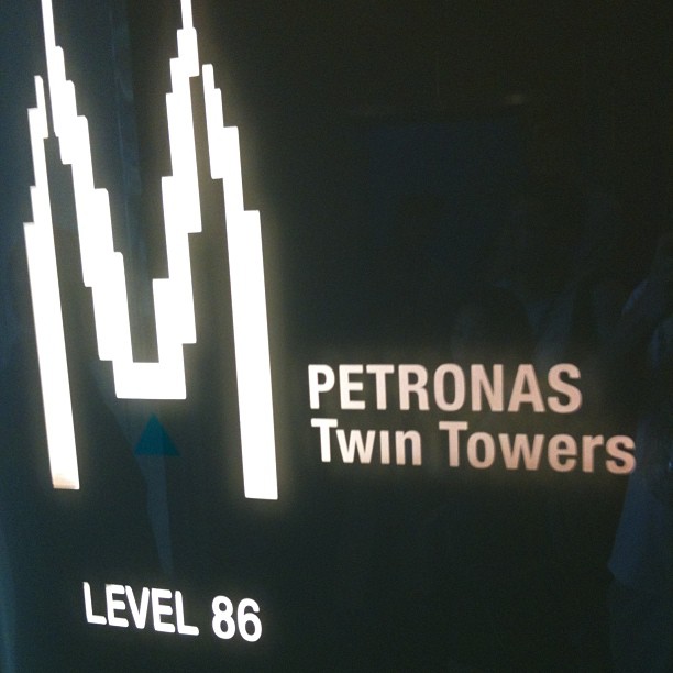 Illuminated sign with a stylized twin-tower outline and the words "PETRONAS Twin Towers" and "LEVEL 86" on a dark background.