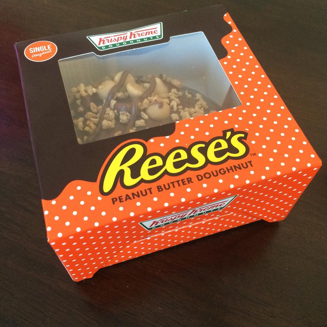 Krispy Kreme single-doughnut box with Reese’s Peanut Butter Doughnut branding and a doughnut visible through the clear window.