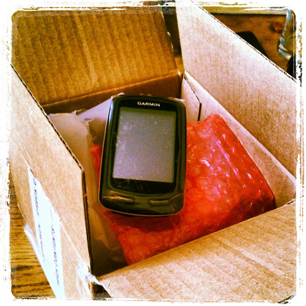 Garmin GPS device resting on red bubble wrap inside an open cardboard box.