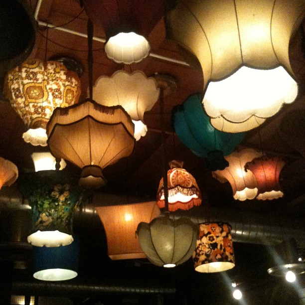 Various vintage-style hanging lamps with colorful fabric shades glow warmly against a dark ceiling.
