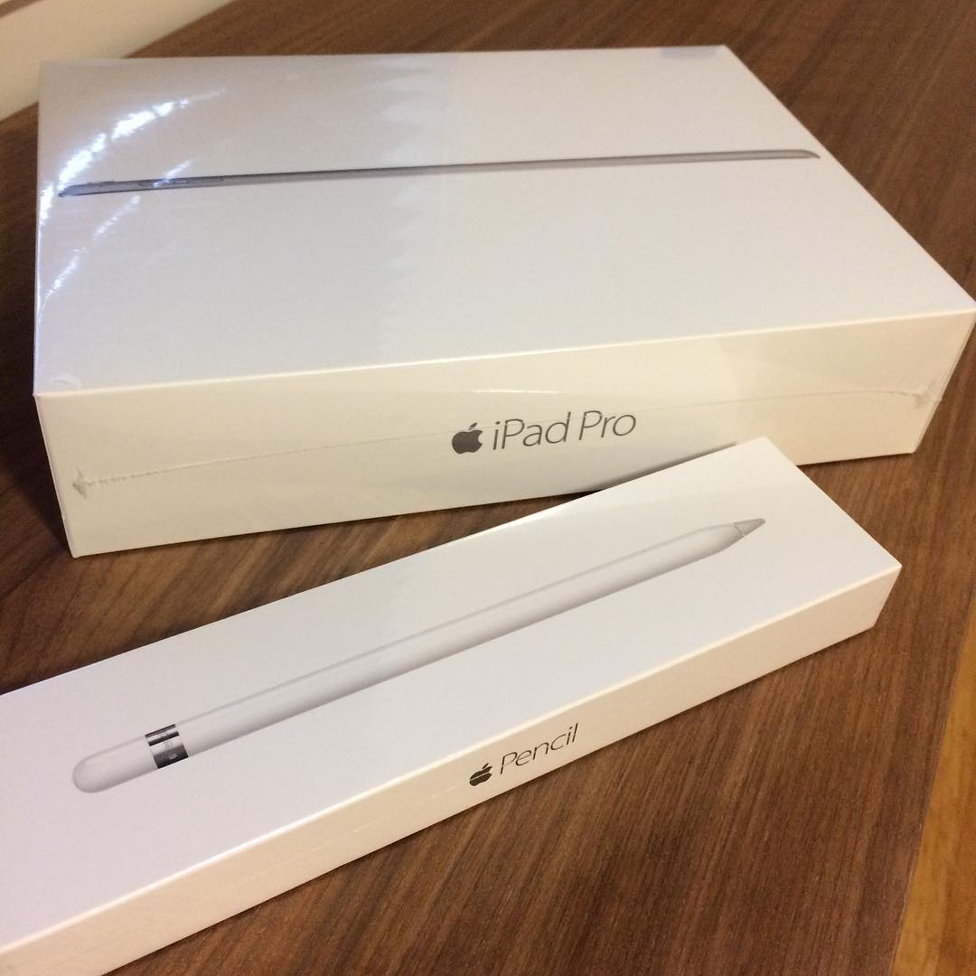 Sealed white iPad Pro box and Apple Pencil box on a wooden table.