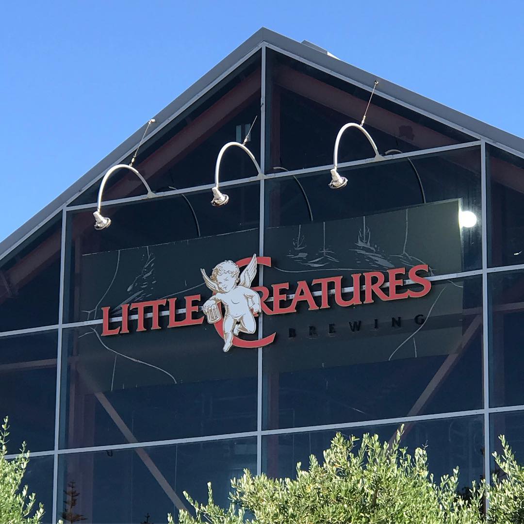 Glass-fronted building with a peaked roof and a red "Little Creatures Brewing" sign featuring a winged cherub.