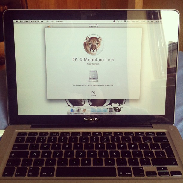 MacBook Pro screen showing the OS X Mountain Lion installation window above the keyboard.